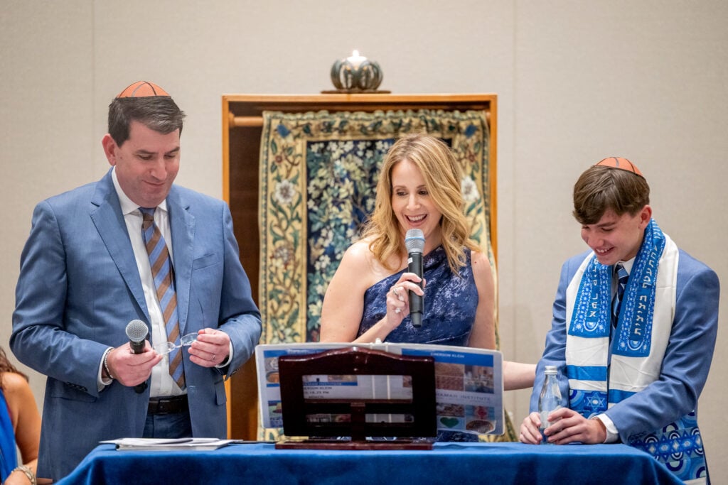 Bar mitzvah student celebrating with the Torah after completing Neshamah's online program, niboca.org