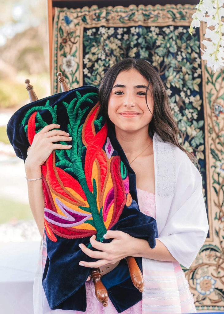 Bat mitzvah student celebrating with the Torah after completing Neshamah's online program, niboca.org