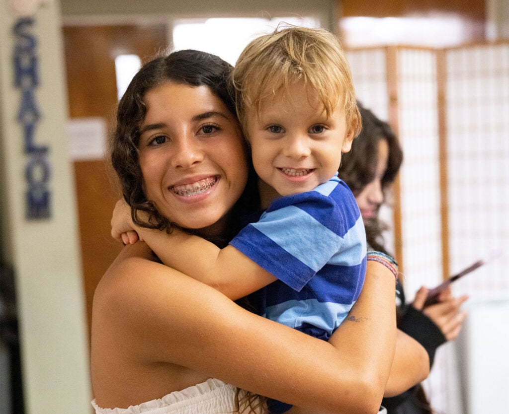 Siblings building and decorating a sukkah together at Neshamah Institute's Hebrew School in Boca Raton, niboca.org